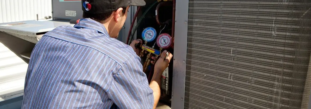 HVAC technician servicing a condenser unit in Timnath